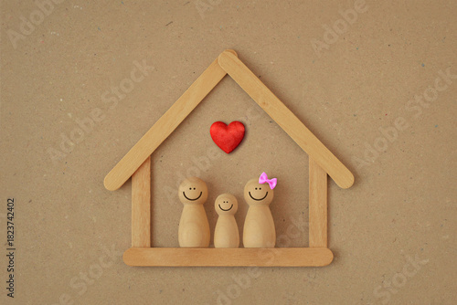 Wooden pawn family in a house made of wooden sticks with heart - Love and family union concept