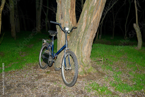 old blue bicycle with flashlight in night park