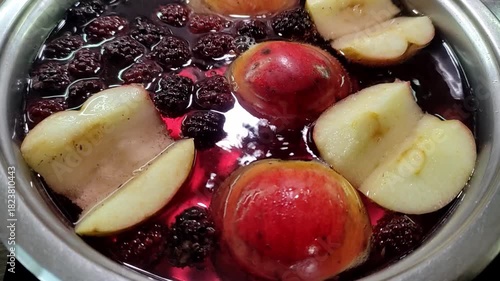 Apples and blackberries are boiled in water in a saucepan to make compote