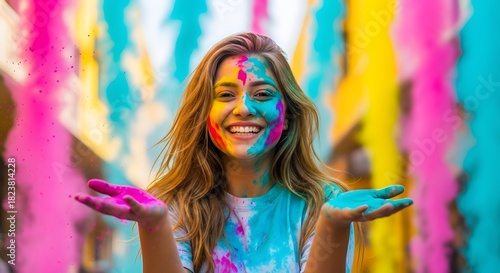 A happy young woman celebrates holi, the hindu festival of colors, with vibrant powder paint covering her face and hands, smiling joyfully