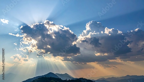 Radiant sunbeams burst from behind fluffy clouds over a distant mountain range