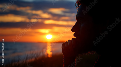A man in deep thought gazing into the horizon at sunset