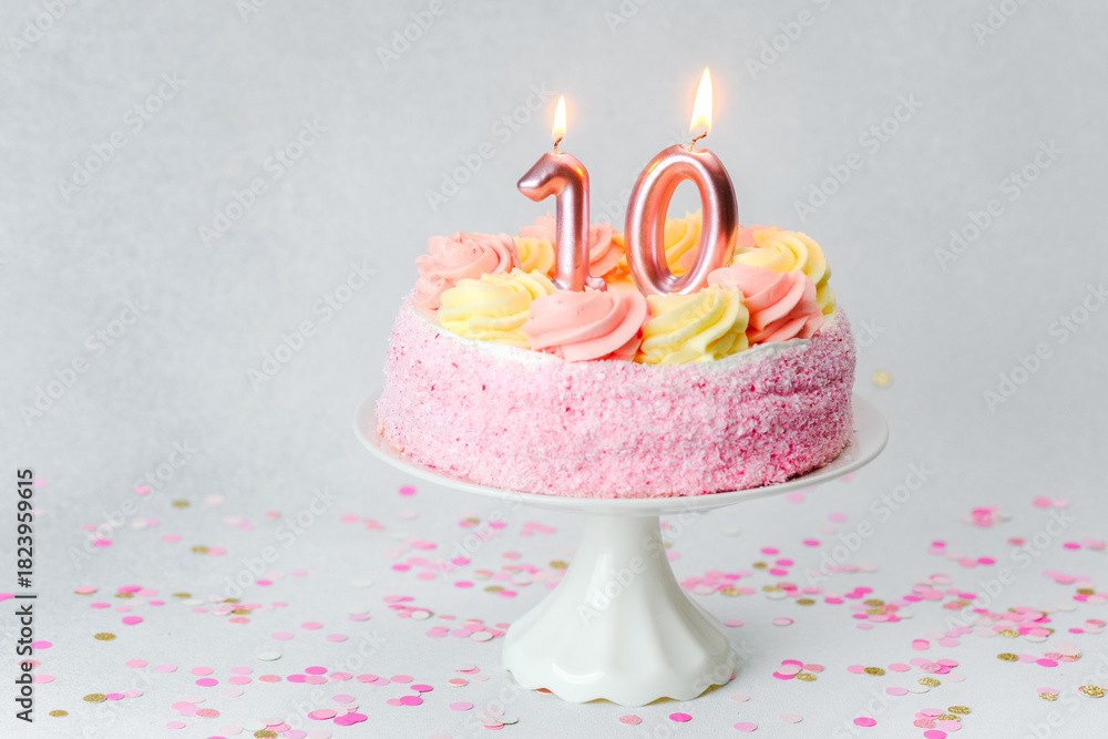 Fototapeta premium Celebrating a tenth birthday with a pink cake and candles on a festive table