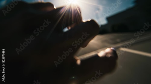 Silhouetted hand and fingers casting shadow against bright sunlight with lens flare and clear blue sky outdoor background