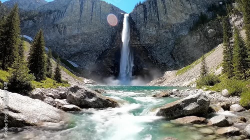 Majestic Alpine Waterfall Plunging into a Shimmering Turquoise River in a Serene Mountain Landscape on a Sunny Day