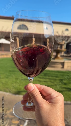 Slow motion closeup shot of a hand swirling a glass of red wine at a wine tasting in Stellenbosch, South Africa.