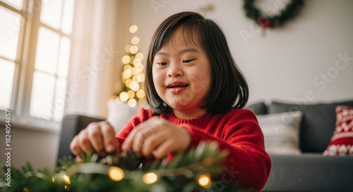 Young girl with Down syndrome decorating Christmas wreath at home  