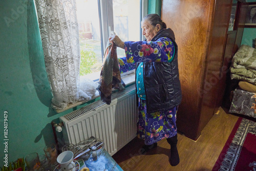 An old country woman in her house is getting ready to go out into the countryside.