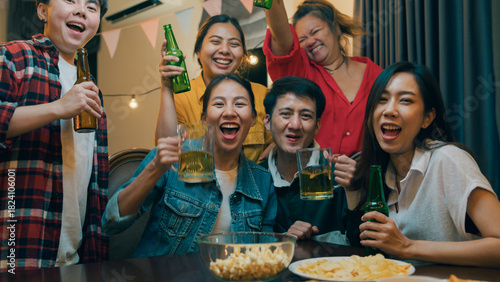 Canvas Print Group of multiethnic adult Asia people use phone greeting friend on remote video call and having hangout party at dining table in night life indoor home
