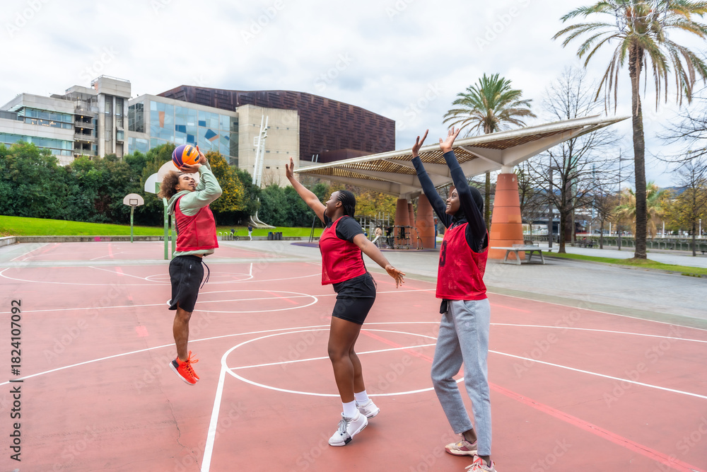 Obraz premium Diverse friends playing basketball together on urban court