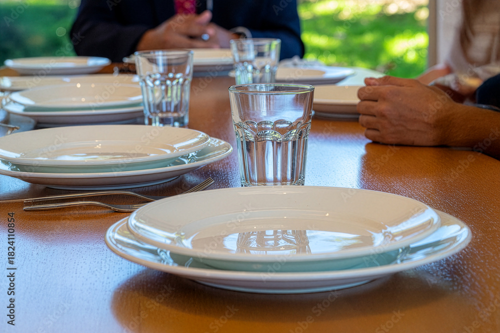Fototapeta premium Dining table setting with clean plates and glasses
