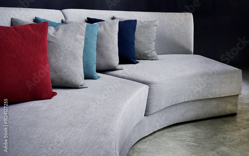 Modern grey curved sofa with colorful accent pillows on polished concrete floor