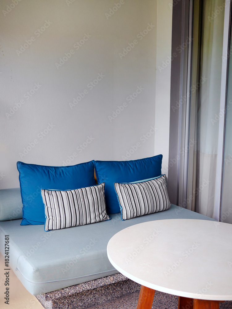 Obraz premium Modern resort balcony seating area with blue daybed pillows and pebble wash builtin sofa