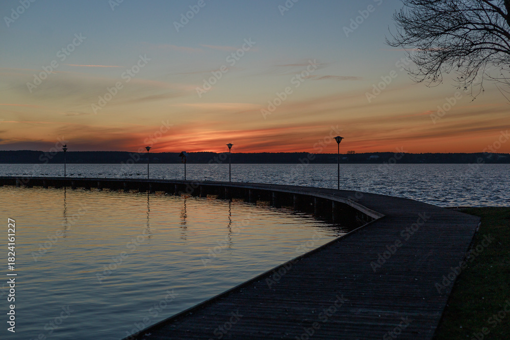Obraz premium Pier curve into sunset lake.Curved pier leads into a lake under sunset colors. Concept of journey metaphor, poster design, emotional storytelling, and inspirational visual