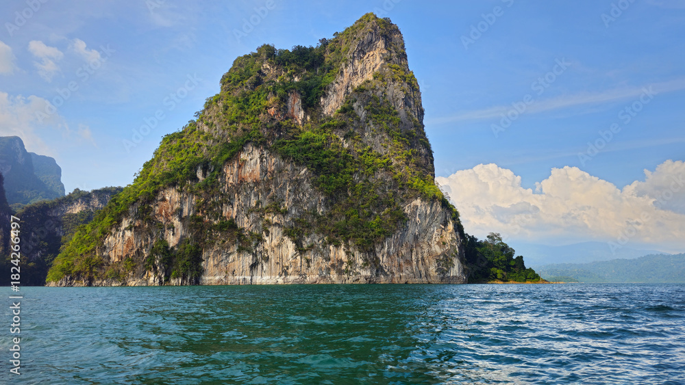 Naklejka premium Cheow Lan Lake with limestone karsts rising from tranquil water, Khao Sok National Park, Ban Ta Khun, Thailand, Southeast Asia.