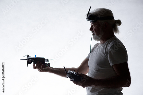 Silhouetted elderly man put a drone in his hand on studio background, modern hobby and technology, human tamed technologies