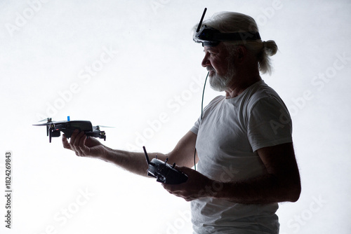 Silhouetted elderly man put a drone in his hand on studio background, modern hobby and technology, human tamed technologies