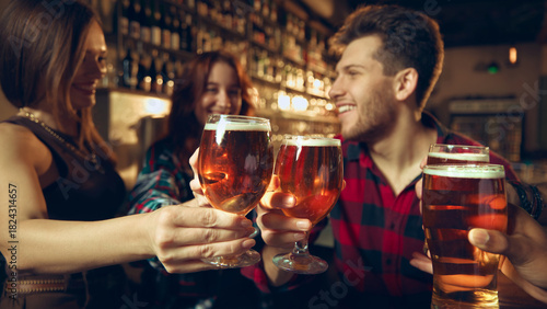 Photography Friends enjoying beer together at bar with shelves of bottles behind them