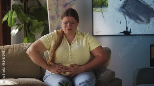 Sad curvy woman holding her stomach, suffering abdominal pain and period cramps