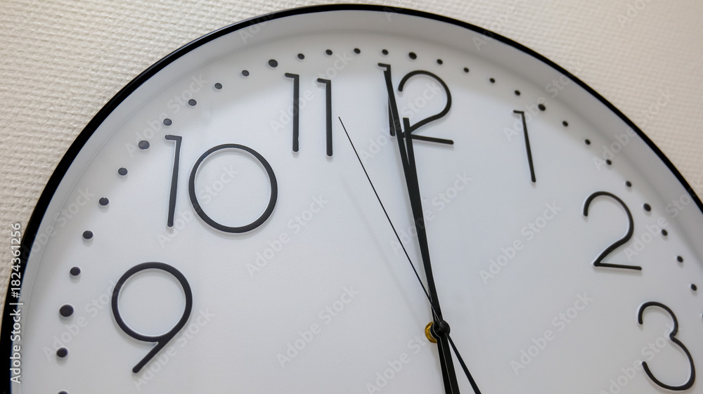 Fototapeta premium Simple white round clock displaying almost noon