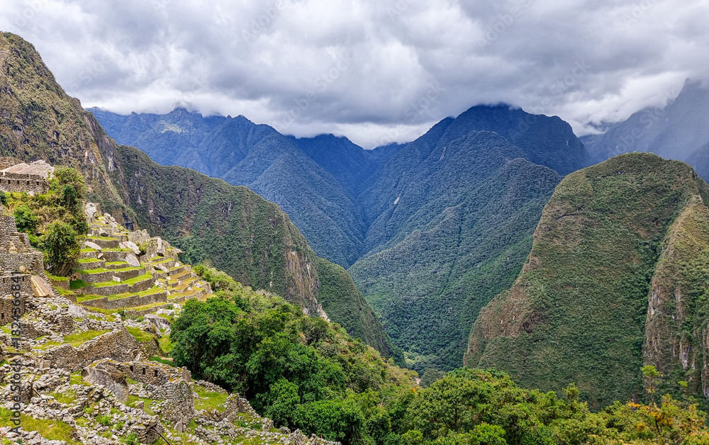 Naklejka premium The ancient Inca city of Machu Picchu, nestled high in the Andes Mountains of Peru. The breathtaking view showcases the iconic terraces, stone ruins, and surrounding green peaks.