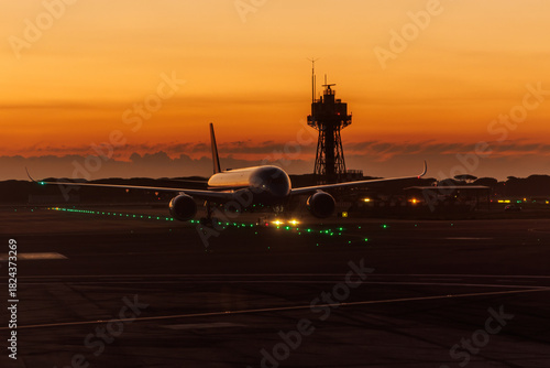 Slika na platnu Airplane taxiing on runway at sunset