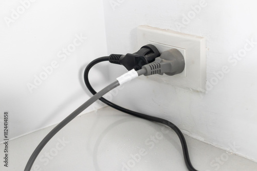 Tableau sur toile Electrical plugs in wall socket with connected cords creating simple home power
