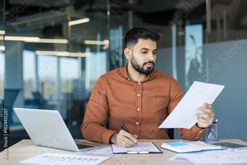 Tableau sur toile Young male professional concentrating on official documentation while writing no