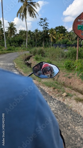 Caucasian couple in their 30s riding motorbike through tropical countryside farmland road helmets on honeymoon adventure exploring remote village Bali Sri Lanka Ceylon Asia agriculture fields travel d