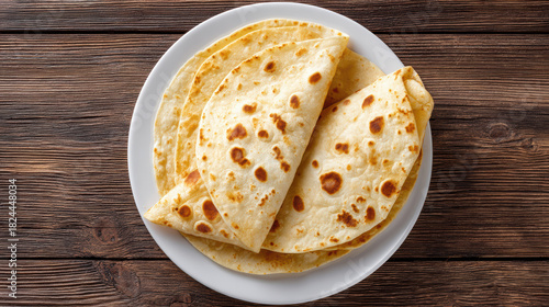 Top view of delicious homemade flatbread tortilla wrap on white plate. comforting and tasty meal on rustic wooden background, simple food ready for cooking