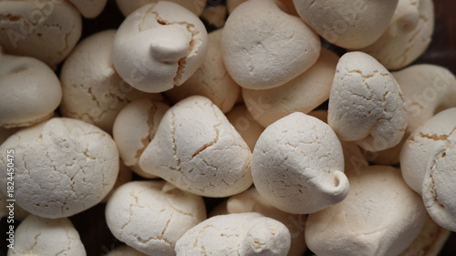 Dry brittle cracked meringues with a crispy sugar crust as a white sweet background of homemade sweets for tea drinking, close-up of a group of light meringues as a banner texture of sweets