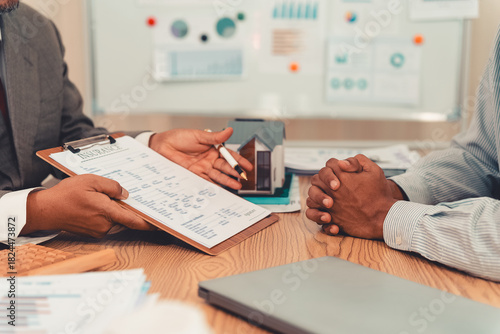 Real estate agent and client sign contract on clipboard on table after signing real estate sales contract along with approved home loan application form.