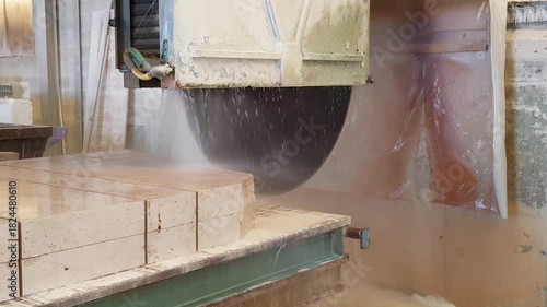 Découpe d'un bloc de calcaire issu d'une carrière, à l'aide d'une scie circulaire et sous aspersion d'eau.