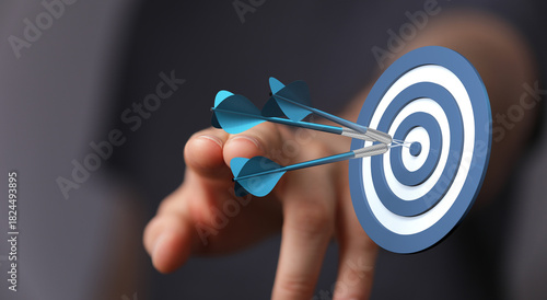 Hand throwing darts at a ta...