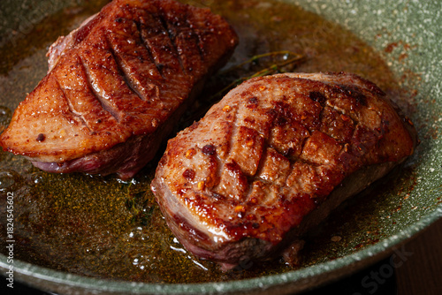 cooking duck breast, in a frying pan, fried, with spices and herbs, close-up, no people,