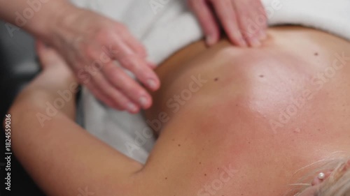 Hands perform gentle back and neck techniques for a woman in a peaceful beauty spa