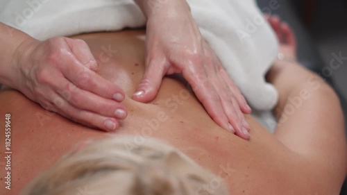 Hands perform gentle back and neck techniques for a woman in a peaceful beauty spa