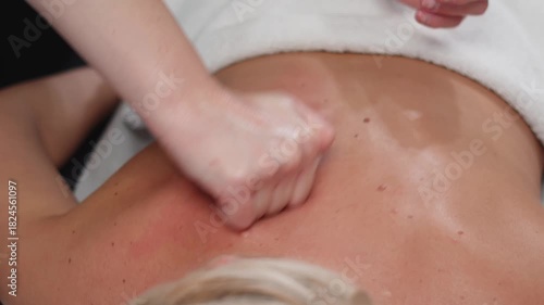 Hands perform gentle back and neck techniques for a woman in a peaceful beauty spa
