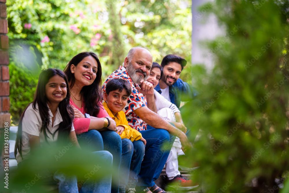 Fototapeta premium Indian family enjoying outdoor bonding time on steps during weekend relaxation