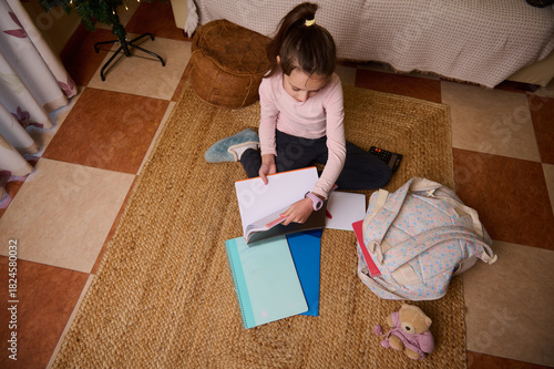 Young Girl Studying At Home With Notebooks, Backpack, And Cozy Rug