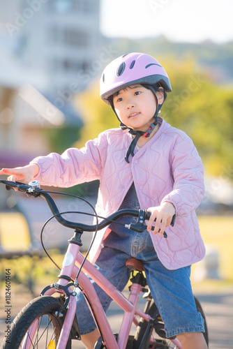 ピンクの自転車に乗る日本の女の子と明るい公園の屋外風景