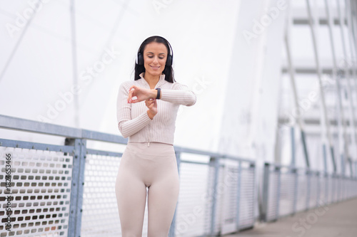 Free Download Sporty woman checking fitness tracker on bridge - GFXLoad