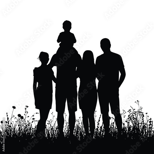 Silhouette of a happy family of five standing in a field at sunset