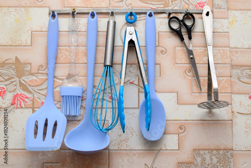 set of silicone and metal kitchen utensils hanging on a metal railing