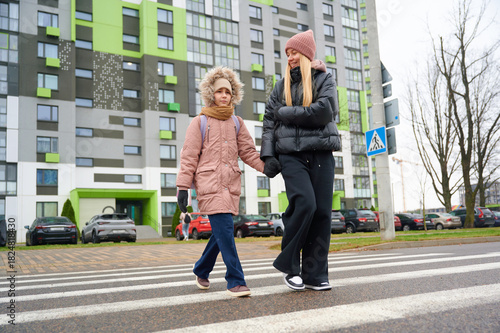 Mother walking with child across urban crosswalk