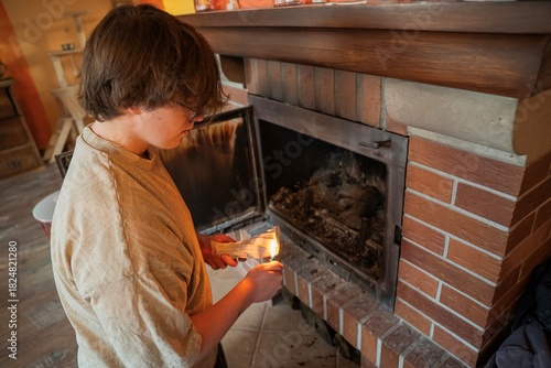 osoba rozpalająca ogień w kominku