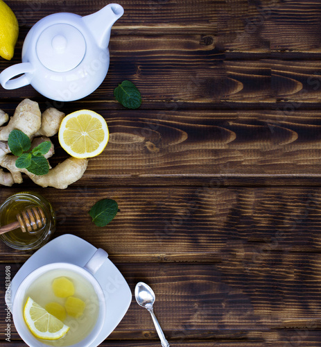 Ginger tea in the white cup and ingredients on a wooden background. Top view.Copy space.