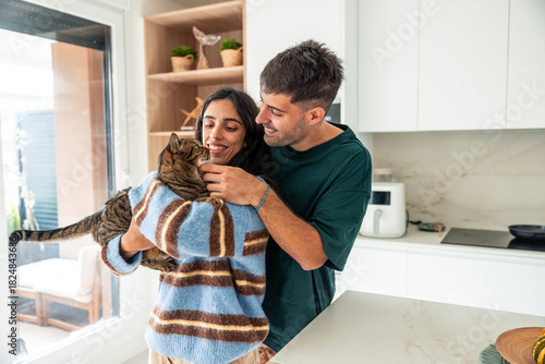 Latin couple embracing pet cat in modern kitchen