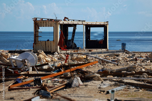 Dilapidated wooden shack and debris on a rocky shoreline with the ocean in the background
