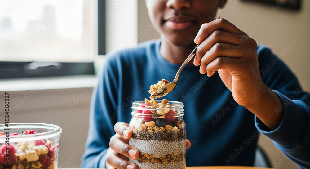Fototapeta premium A young boy enjoys a delicious and nutritious homemade layered breakfast parfait with fresh berries, oats, and chia seeds